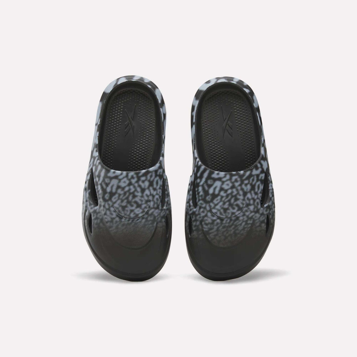 The Reebok DMX Recovery Mules feature a black and gray leopard print, shown from above on a white background—ideal recovery footwear after long days.