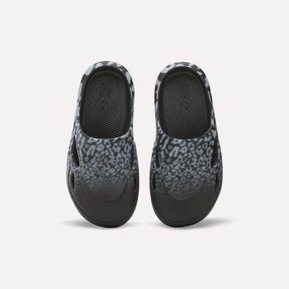 The Reebok DMX Recovery Mules feature a black and gray leopard print, shown from above on a white background—ideal recovery footwear after long days.