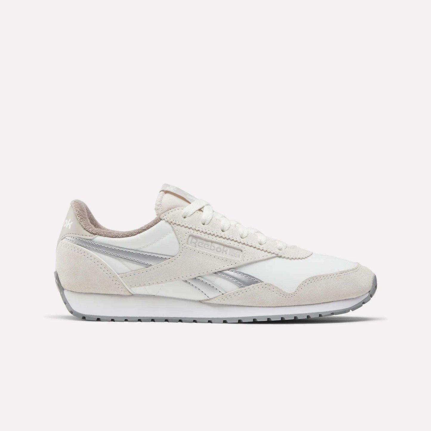 The Reebok Women's Classic AZ Shoes feature a white and beige colorway with silver accents, vintage details, low-top design, lace-up closure, and rubber sole—making them a stylish addition to any women’s sneaker collection. Shown on a white background.