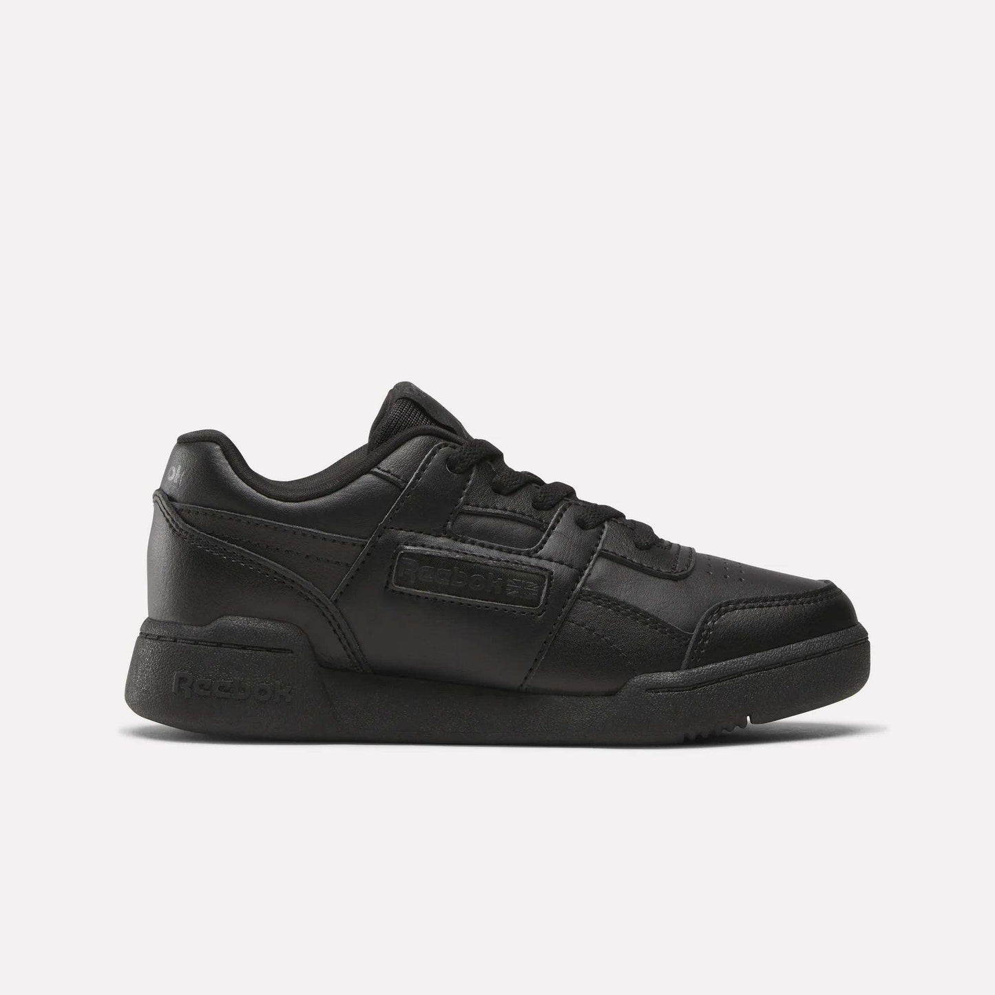 The Reebok Workout Plus Shoes for little kids feature a black low-top design, lace-up closure, and rubber sole, making them stylish and sporty. Displayed on a plain white background.