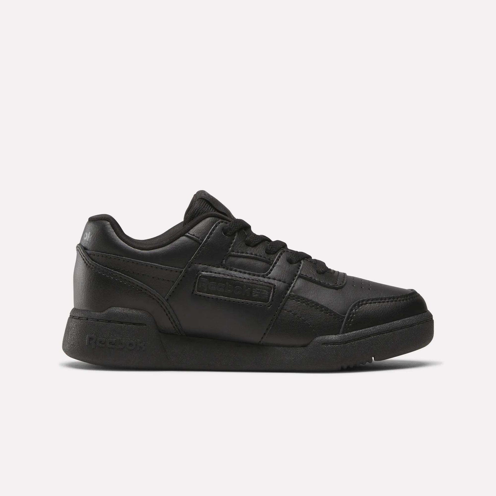 The Reebok Workout Plus Shoes for little kids feature a black low-top design, lace-up closure, and rubber sole, making them stylish and sporty. Displayed on a plain white background.