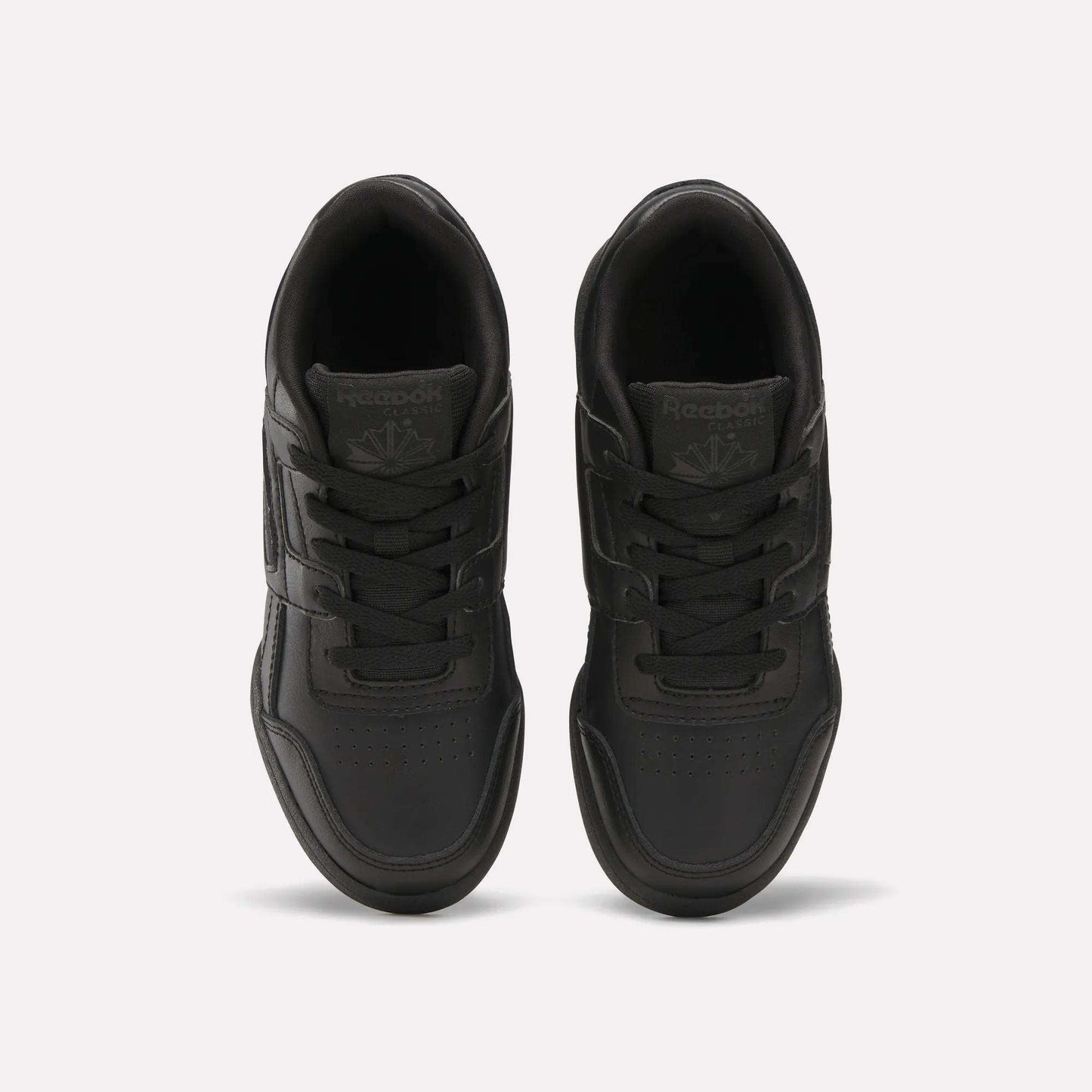 A pair of Reebok Workout Plus Shoes for little kids in black, shown from above on a white background, highlighting the laces, stitched details, and Reebok logos on the tongues.