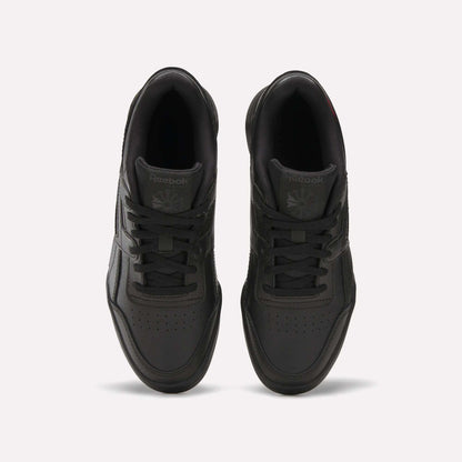 Top view of a pair of black Reebok Workout Plus Shoes for big kids with laces, displayed side by side on a white background. The Reebok logo appears on the tongue of each sneaker.