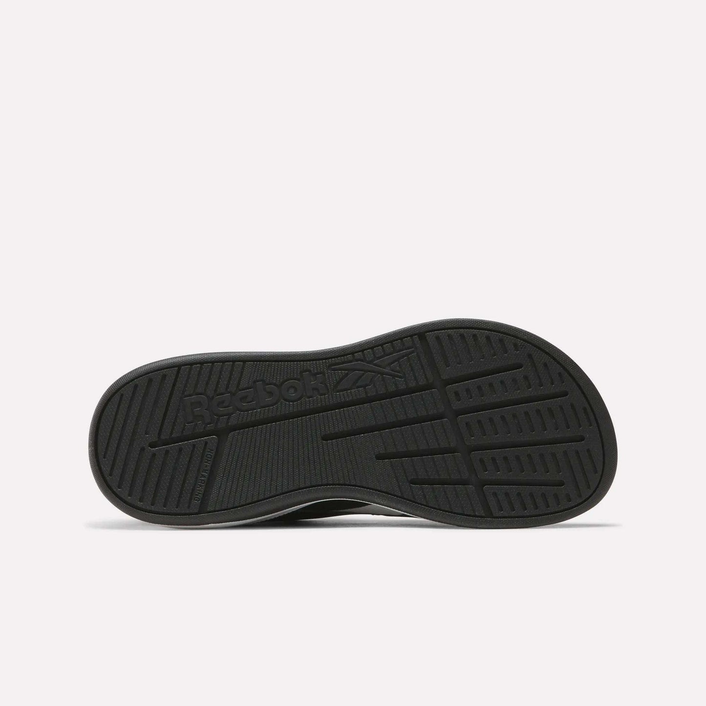 The Nano Play Slip-On Shoes for little kids by Reebok are shown from the bottom, featuring a black sole with the Reebok logo and textured tread for grip against a plain, light background that highlights these athletic shoes.