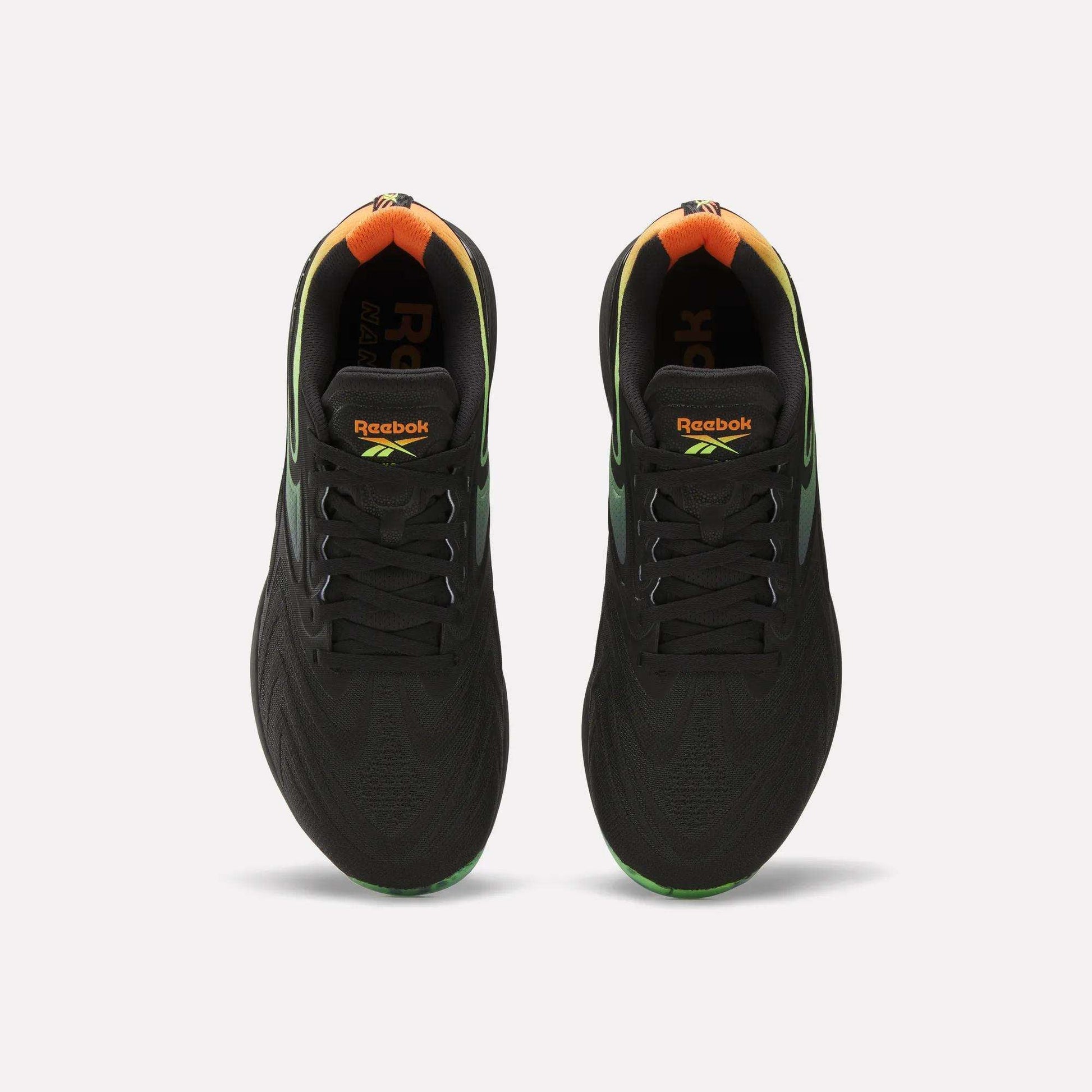 A top view of the Reebok Nano X5 Edge Training Shoes in black, featuring gradient green and orange heel accents, Flexweave support material, and vibrant Reebok logos on the tongue.