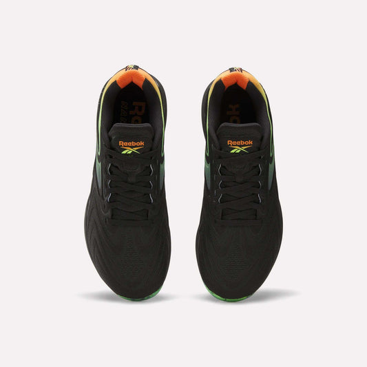 A top view of the Reebok Nano X5 Edge Training Shoes in black, featuring gradient green and orange heel accents, Flexweave support material, and vibrant Reebok logos on the tongue.