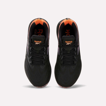 Top view of Women's Nano X5 Edge Training Shoes by Reebok in black with orange heel and inner accents, Reebok logo on tongue and insole. Shoes shown side by side on a white background.