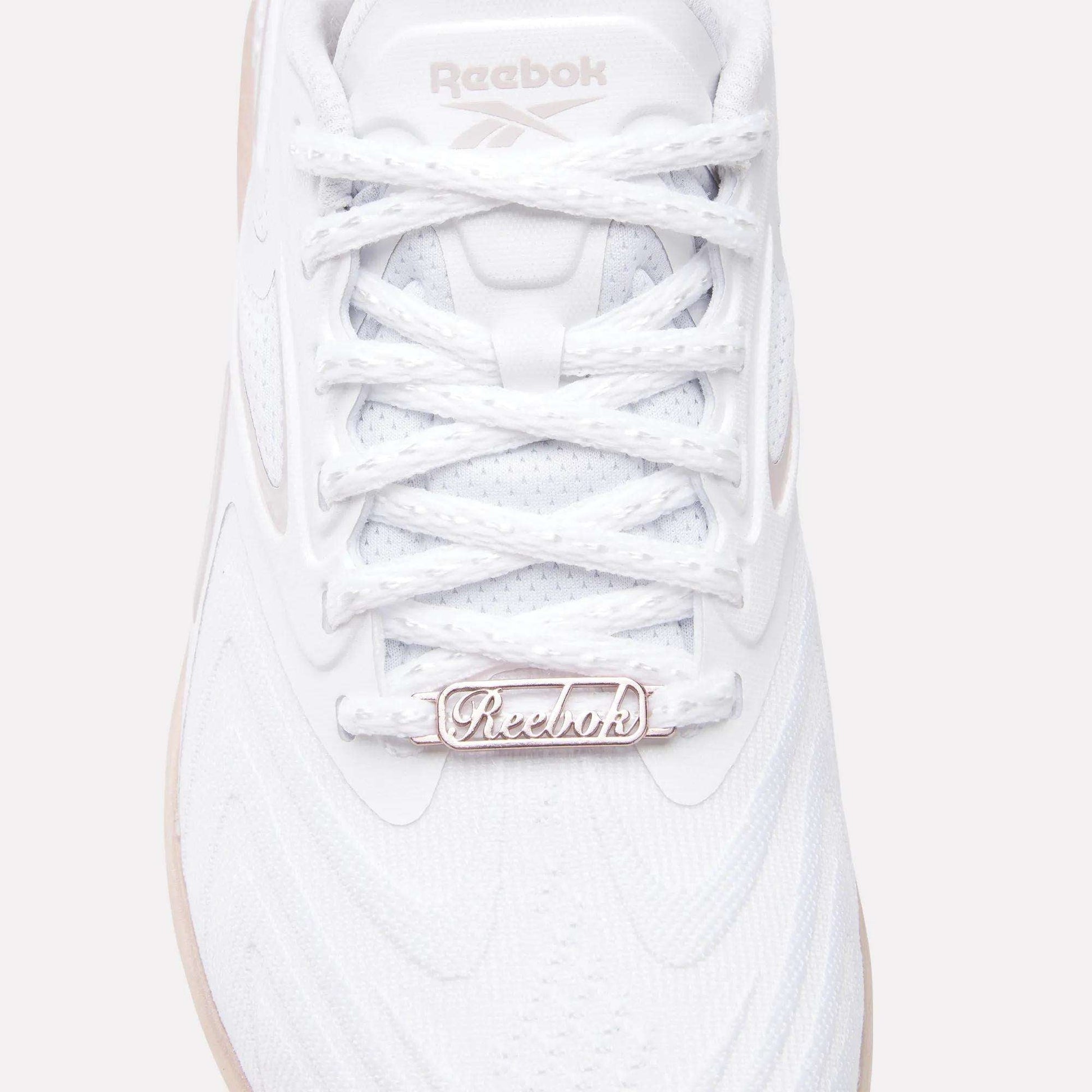 Close-up of the Women's Nano X5 Edge Training Shoes by Reebok, featuring a white textured upper, detailed laces, and a metallic logo tag—ideal for HIIT or daily workouts.