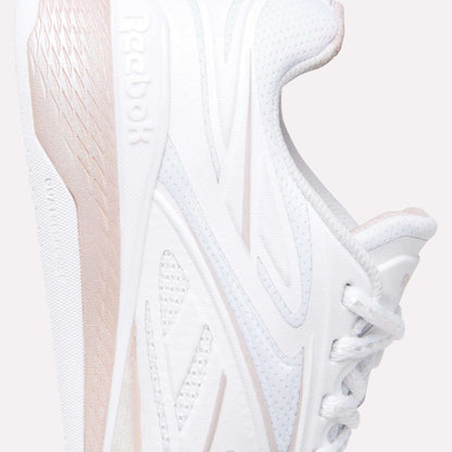 Close-up of the Reebok Women's Nano X5 Edge Training Shoes in white with light pink accents, featuring side logo, textured midsole, and partial laces set against a light background.