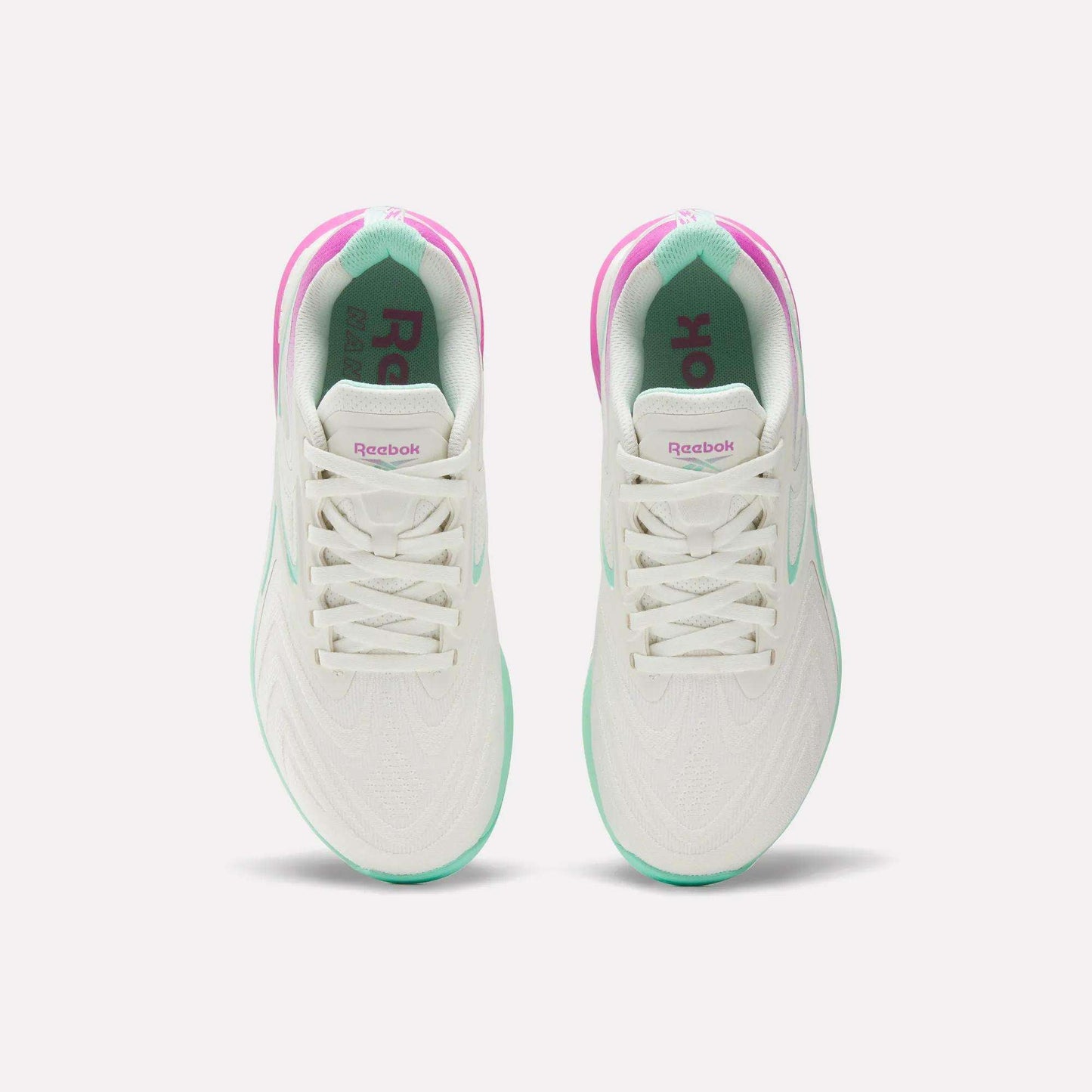 Top view of Women's Nano X5 Edge Training Shoes by Reebok, featuring pink and green accents, white laces, and branded tongues—ideal for HIIT—displayed side by side on a plain white background.