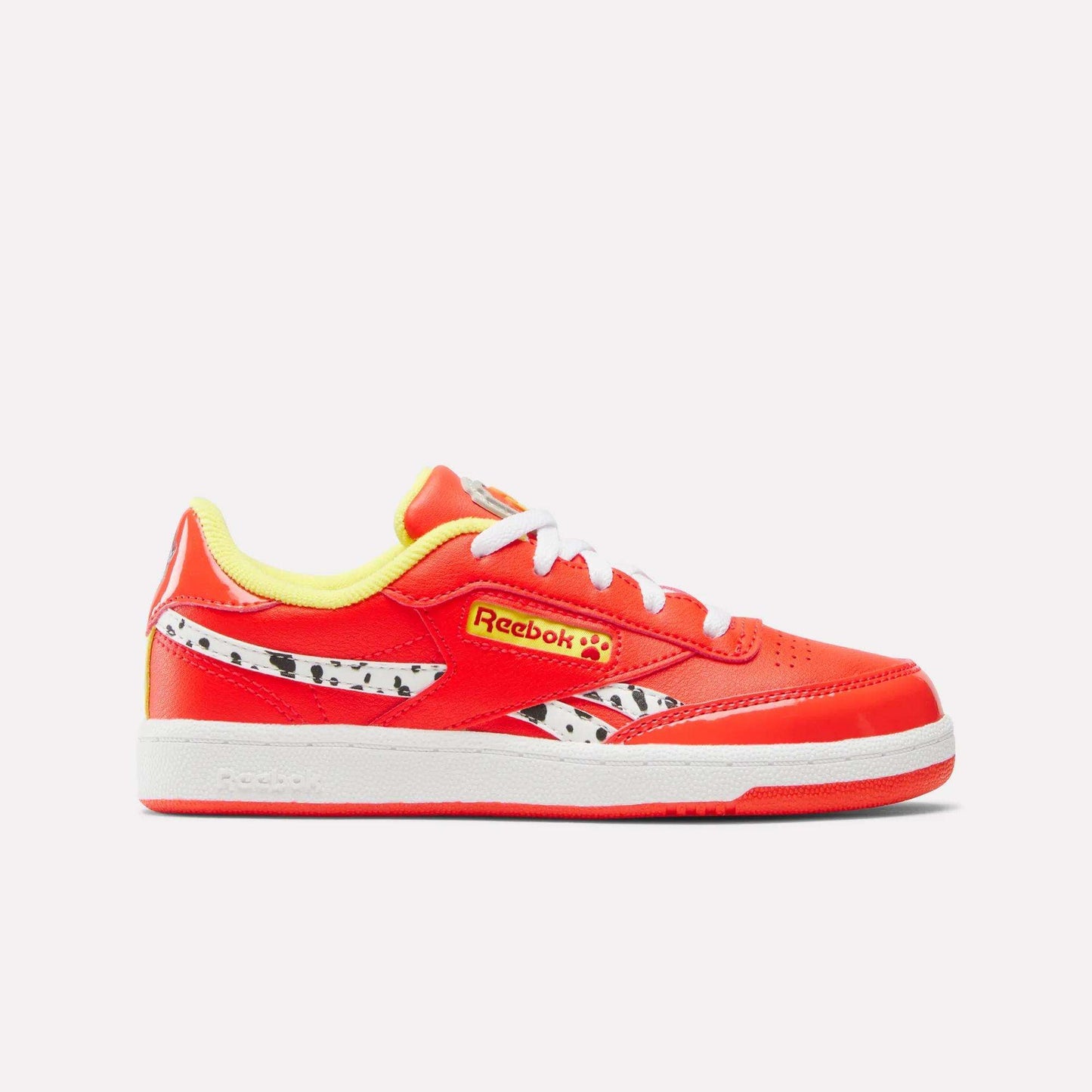The Reebok x Paw Patrol Club C Revenge Shoes for little kids feature a bright red design with white laces, yellow accents, a black-and-white spotted side pattern, retro tennis style, yellow lining, and a comfy white sole.