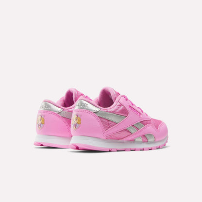 Two pink Reebok x Paw Patrol Classic Nylon Shoes for little kids, featuring silver accents and a blonde princess graphic on the heel. Made from suede for comfort. Shown on a plain white background.