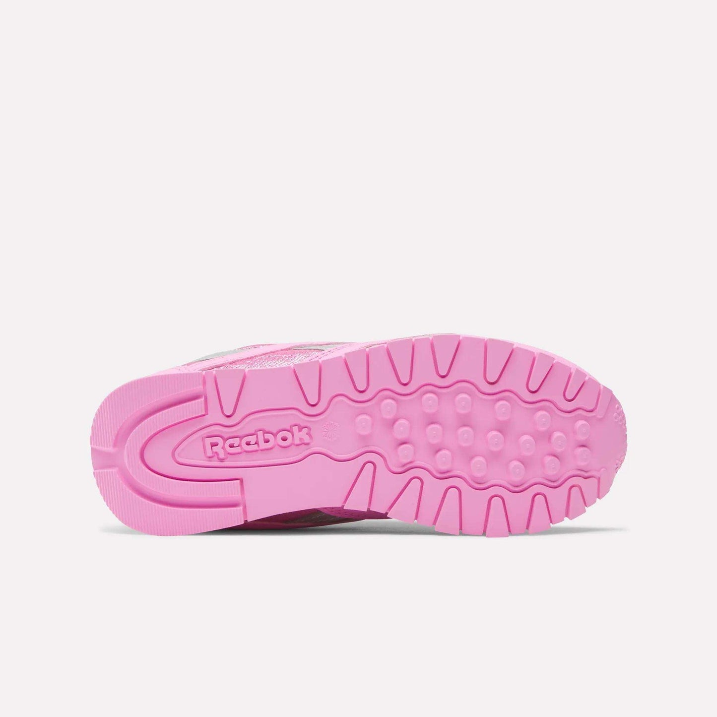 The image displays the sole of a pink Reebok x Paw Patrol Classic Nylon Shoe for little kids, with the Reebok logo and a textured grip pattern on a white background.