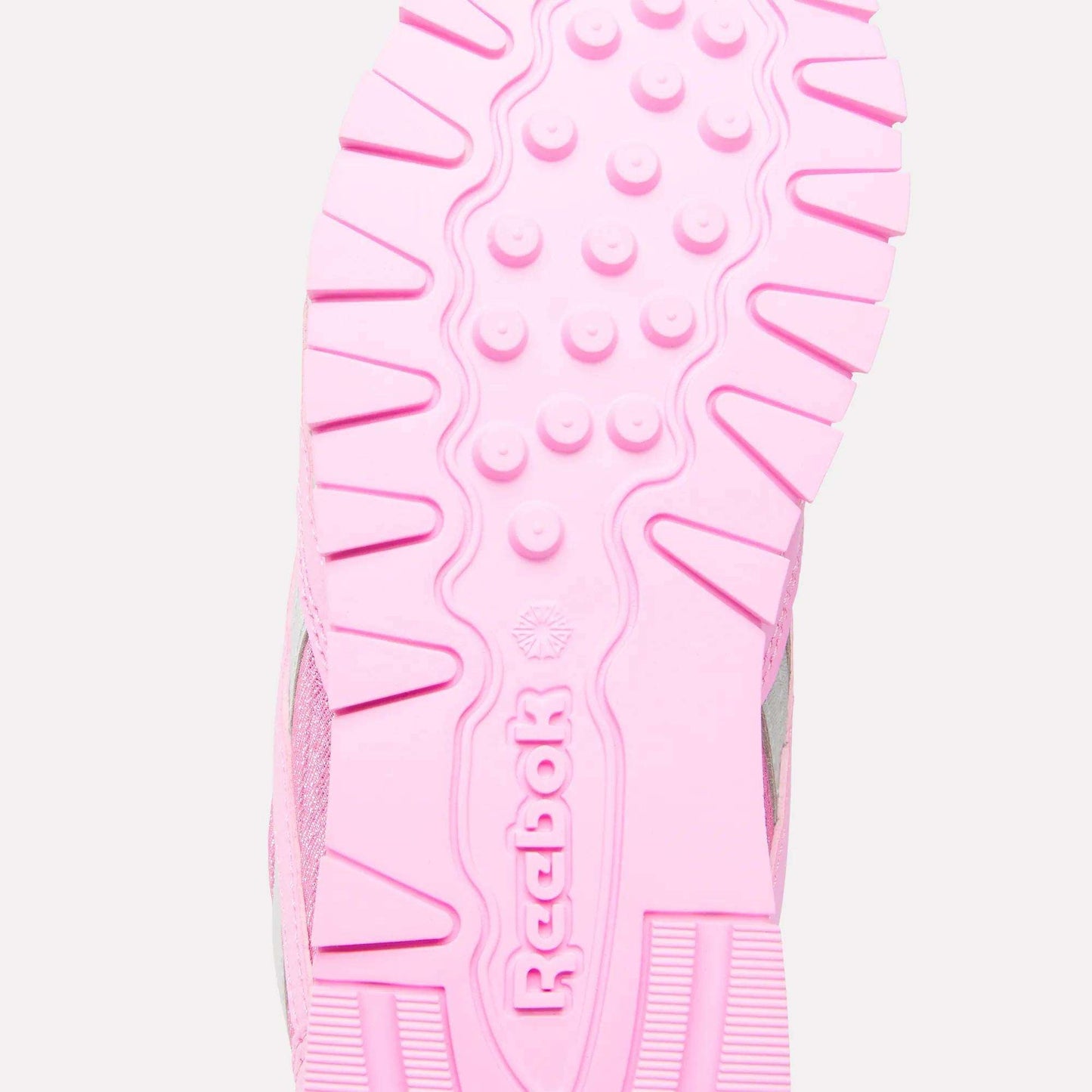 Close-up of the pink sole of Reebok x Paw Patrol Classic Nylon Shoes for little kids, featuring the Reebok brand name and logo in the center, with textured patterns and grooves for added grip.