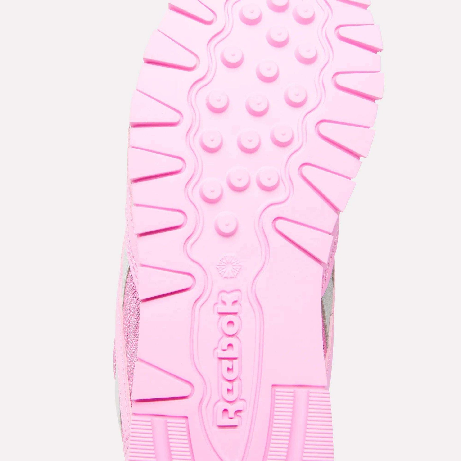 Close-up of the pink sole of Reebok x Paw Patrol Classic Nylon Shoes for little kids, featuring the Reebok brand name and logo in the center, with textured patterns and grooves for added grip.