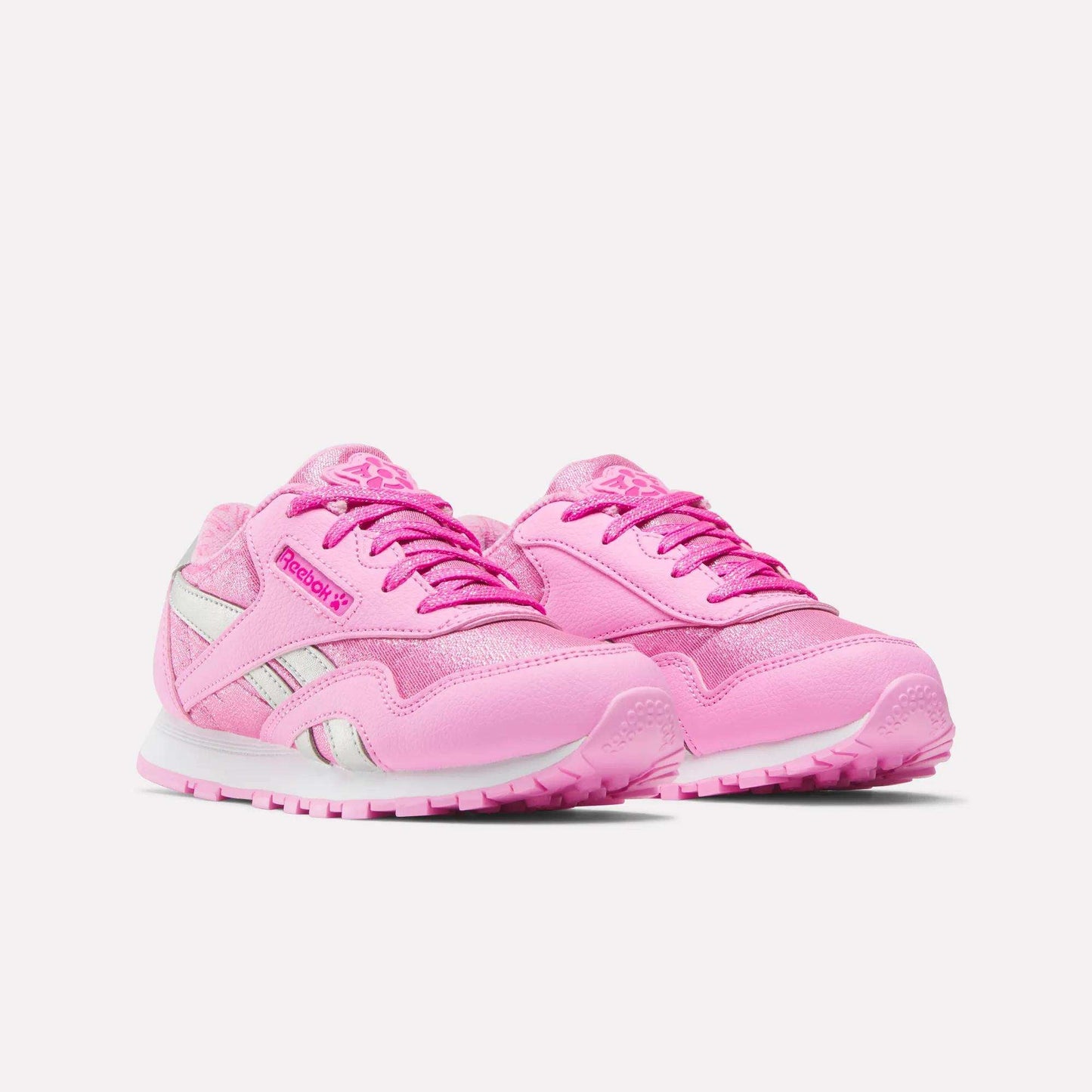 A pair of Reebok x Paw Patrol Classic Nylon Shoes for little kids in bright pink with white and silver accents, featuring laces and a chunky sole, are showcased on a plain white background.