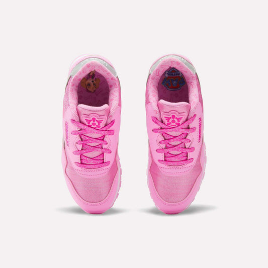 A pair of pink Reebok x Paw Patrol Classic Nylon Shoes for little kids, featuring floral designs on the tongues and cartoon graphics inside the heel, shown from above on a white background.