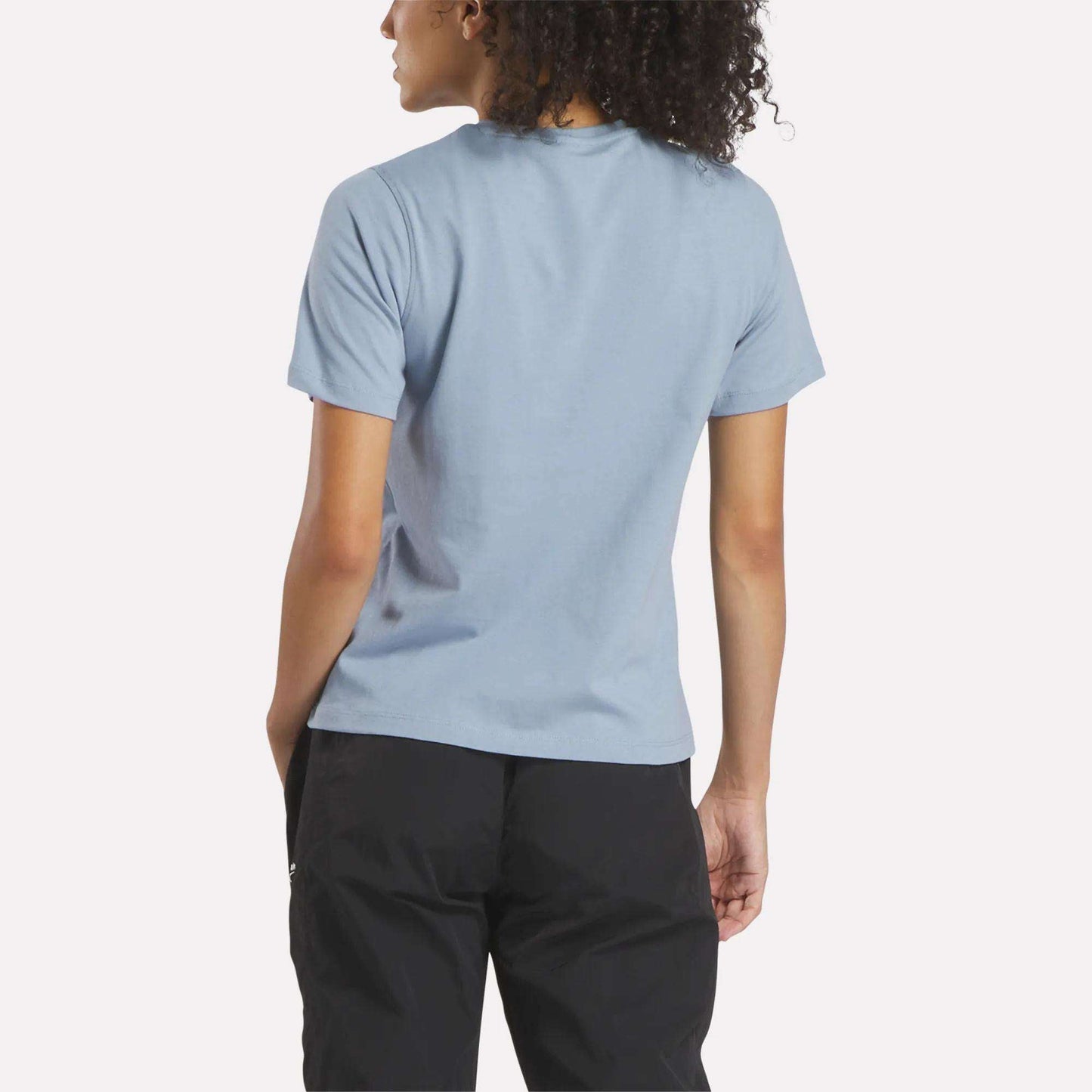 A woman wearing a blue Reebok Women's Big Logo Crewneck Short Sleeve Tee.