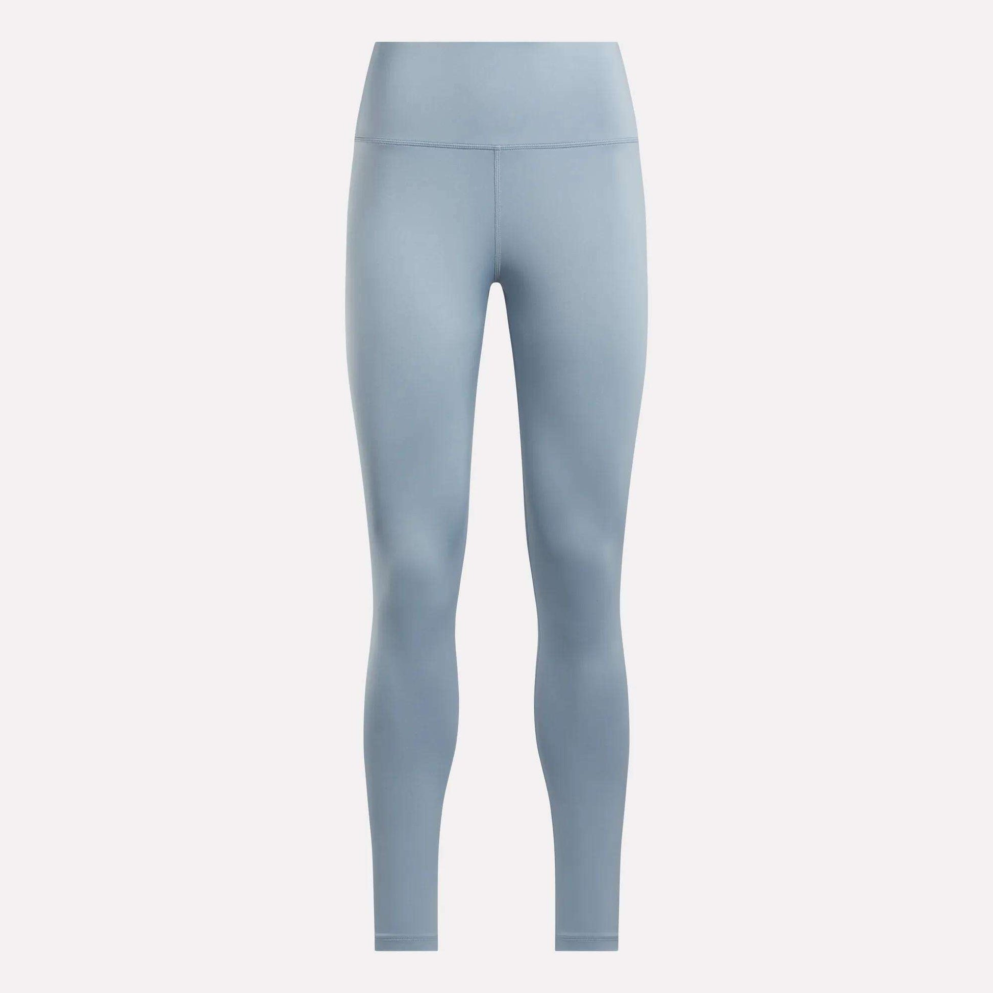 The Reebok Women's Core High-Rise Leggings in light blue feature a seamless, high-waisted, full-length design and are made with RBK-DRY fabric. Shown on a plain white background for a sleek look with no visible patterns or logos.