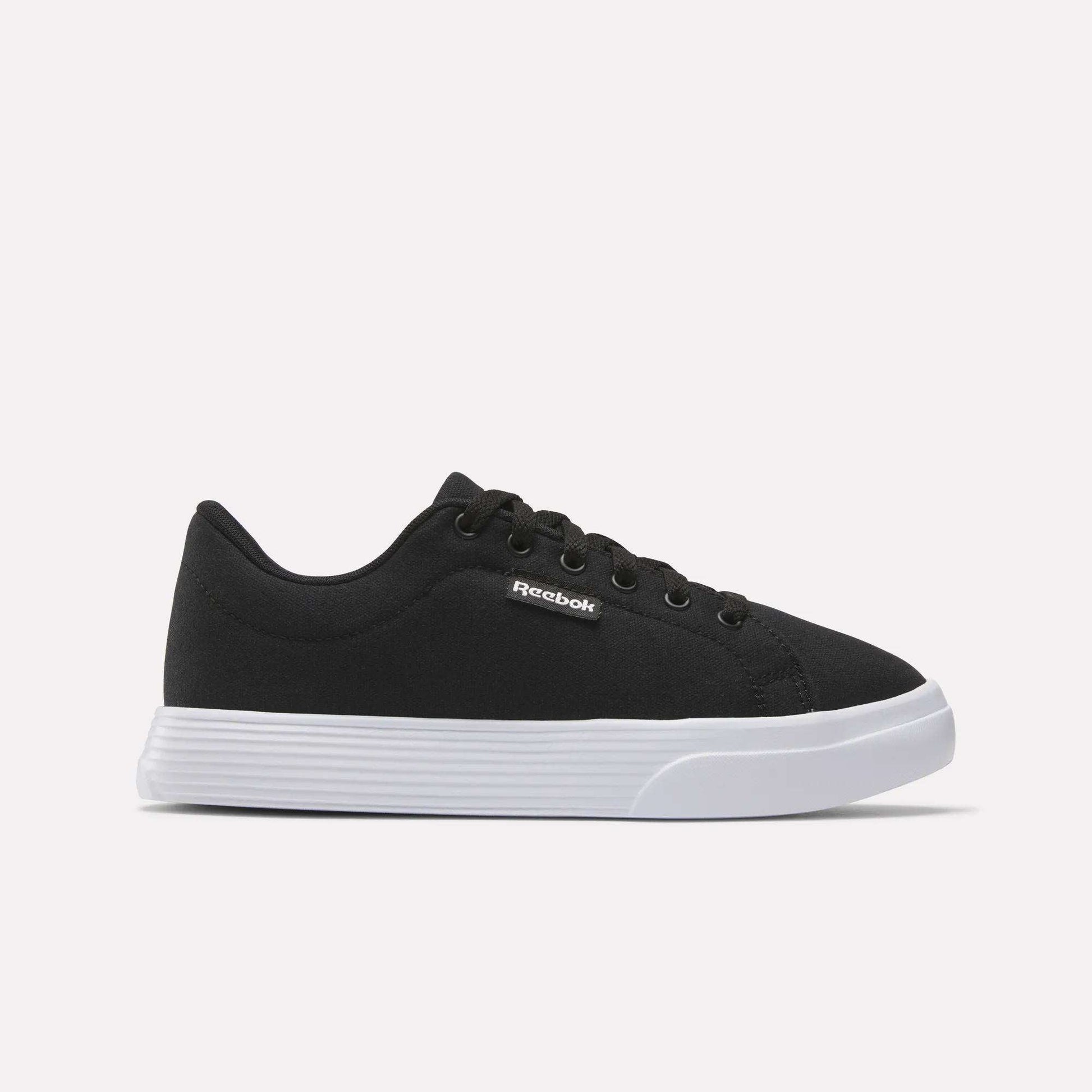 The Reebok Women's OnLux Court Lite Walking Shoes feature a black design with black laces and a white rubber sole, displayed in side profile on a light background—ideal for comfortable all-day walking.