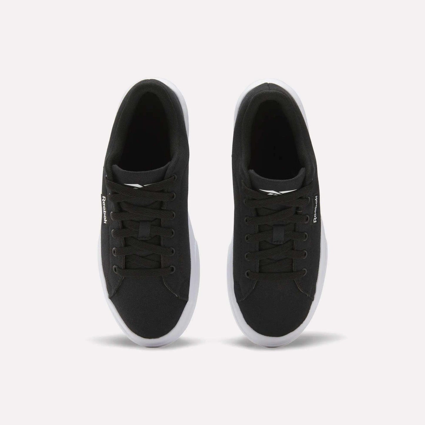 The Reebok Women's OnLux Court Lite Walking Shoes are black sneakers with white soles and black laces, shown from above on a plain white background. Their minimalist design makes them perfect for everyday wear.