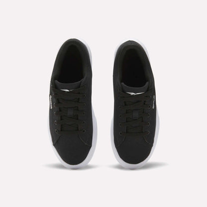 The Reebok Women's OnLux Court Lite Walking Shoes are black sneakers with white soles and black laces, shown from above on a plain white background. Their minimalist design makes them perfect for everyday wear.