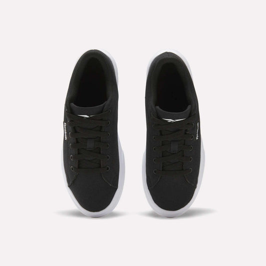The Reebok Women's OnLux Court Lite Walking Shoes are black sneakers with white soles and black laces, shown from above on a plain white background. Their minimalist design makes them perfect for everyday wear.