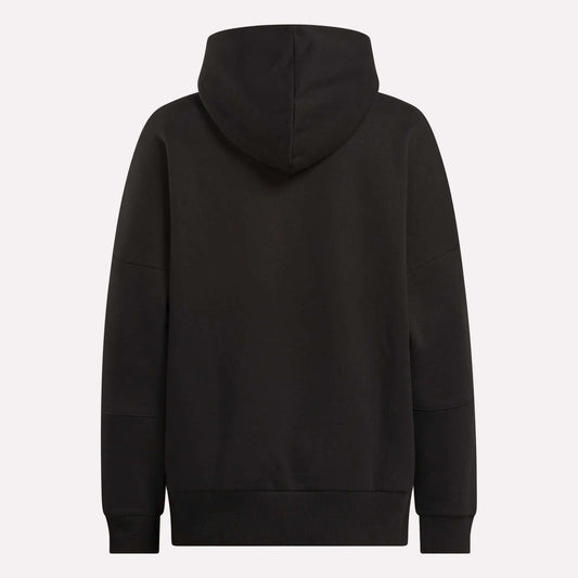 The Reebok Women's Lux Hoodie is shown from the back in plain black, with an oversized fit, long sleeves, and the hood up. It has no visible logos or patterns—ideal for a relaxed, cozy look.