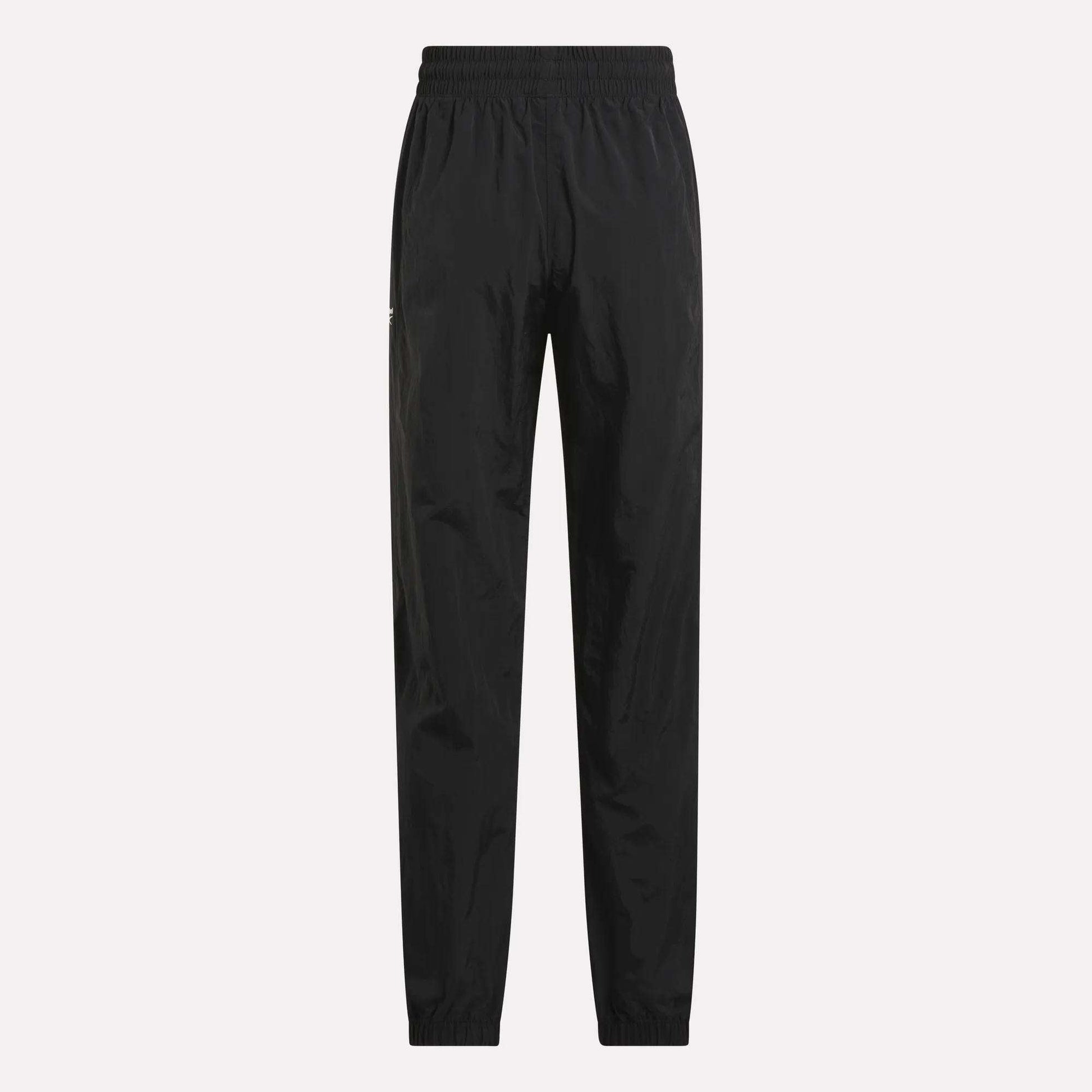 Women's Vector Track Pants by Reebok, shown in black on a plain light background. These feature an elastic waistband and cuffs, straight-leg fit, and lightweight shiny material for a retro-inspired look.