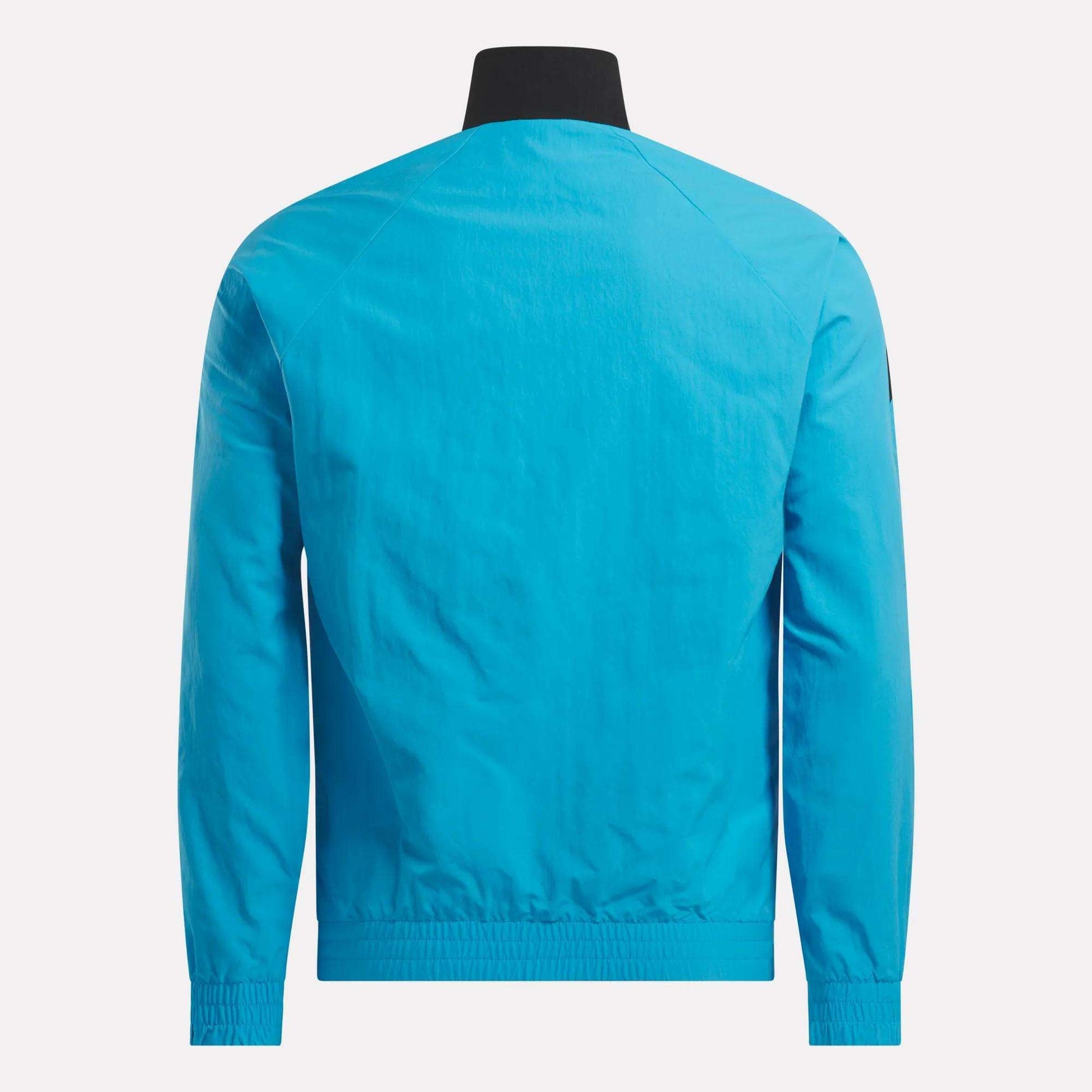 The back view shows the Men's Classics Track Top by Reebok in bright blue, with a black collar, elastic cuffs and hem, and lightweight fabric. The back has no visible logos or designs for a clean, casual look.