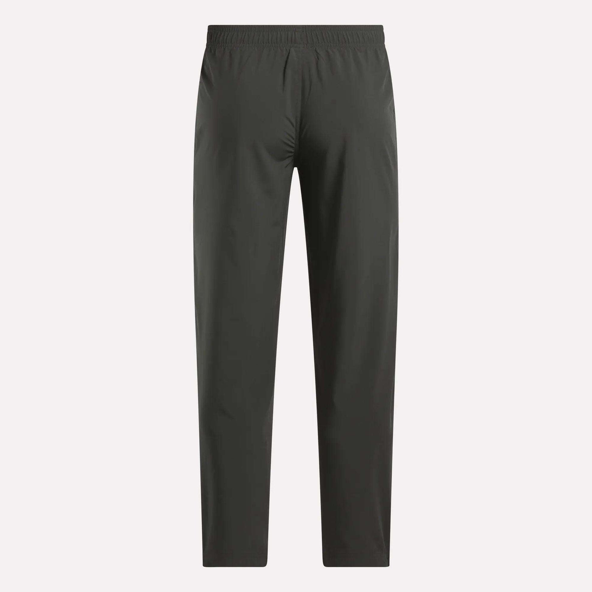 Reebok Men's Train Woven Unlined Pants in dark gray feature a straight-leg design and elastic waistband, ideal as lightweight workout or gym pants. Shown against a light background.
