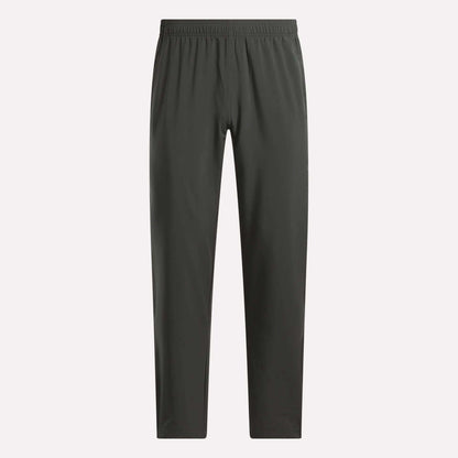 Reebok Men's Train Woven Unlined Pants in dark gray, featuring a straight-leg cut and elastic waistband. Lightweight and ideal for workouts, shown against a plain light background.