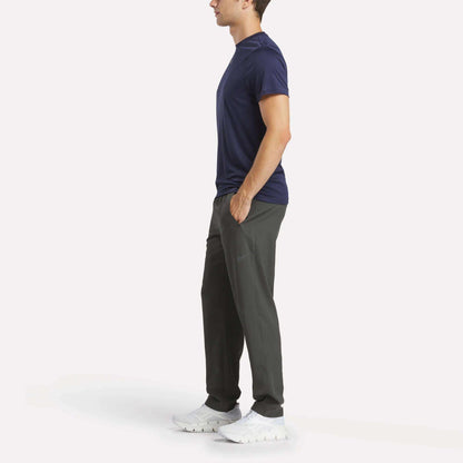 A man in a blue shirt and Reebok Men's Train Woven Unlined Pants.