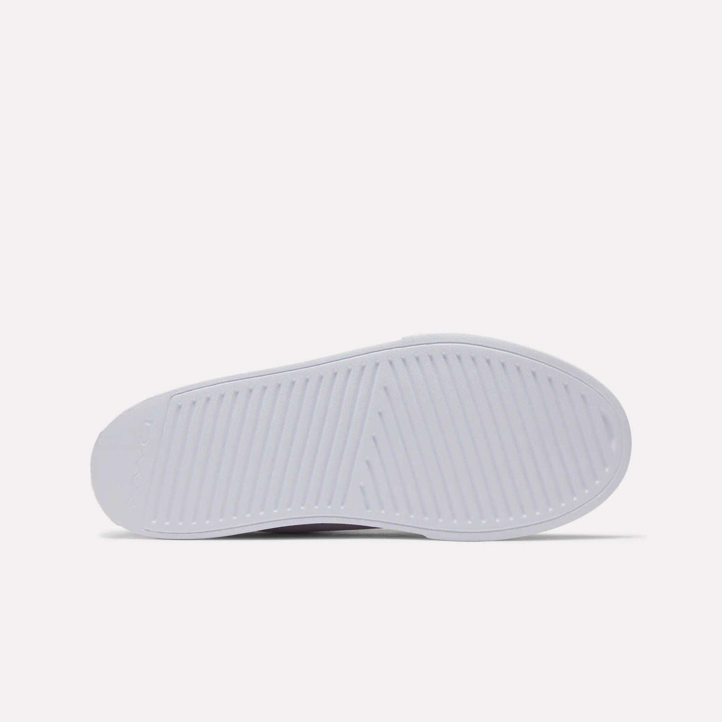 The image shows the sole of a white Women's OnLux Court Lite Walking Shoe by Reebok, viewed from the bottom. The sole has a textured pattern with diagonal and crosswise grooves for traction. The background is plain and light-colored.