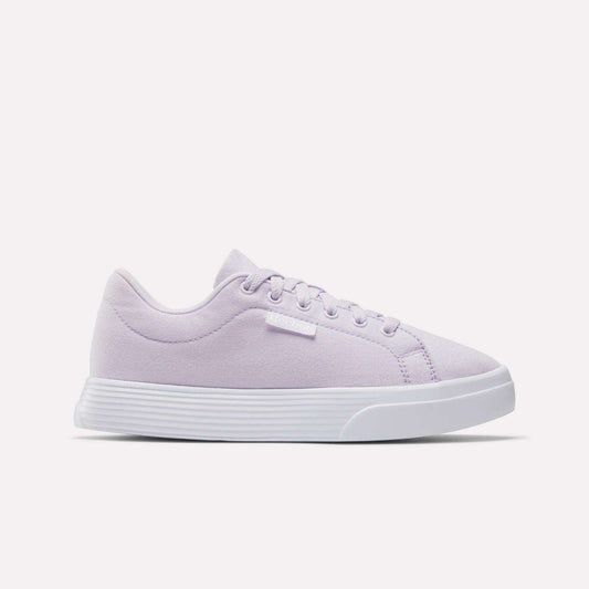 The Reebok Women's OnLux Court Lite Walking Shoes in light purple feature a white sole, white laces, and a small white brand tag. These comfortable sneakers are perfect for all-day wear and are shown on a plain white background.