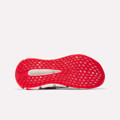 The image shows the bottom of a Reebok Women's FloatZig 2 AHA Running Shoe, featuring a bright red, grid-patterned sole with energy-returning cushioning in the cutout section. The background is plain white.