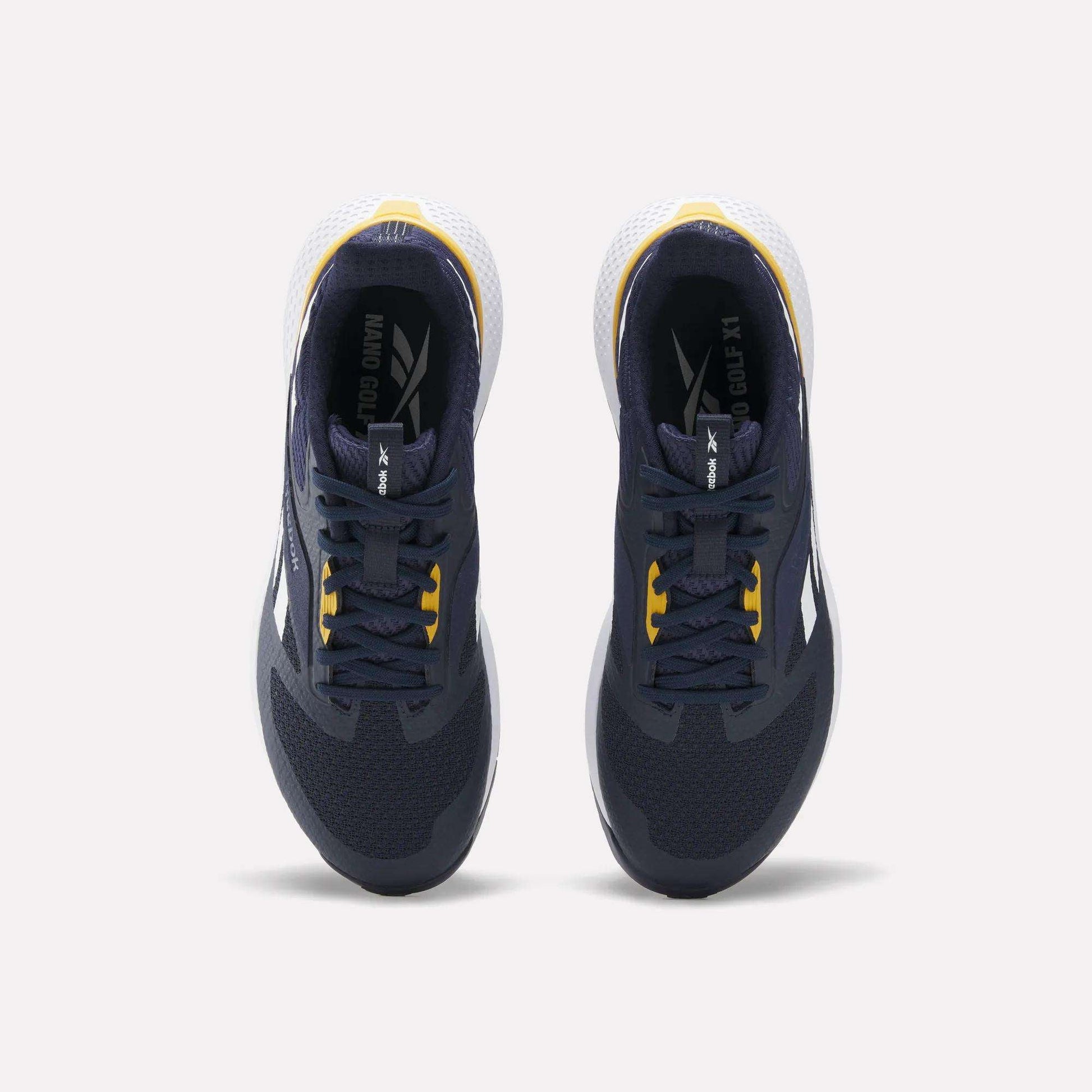 Top view of a pair of Reebok Nano Golf Shoes in dark navy with yellow accents, featuring a lightweight FlexWeave upper, white heel detail, and white outsole, placed side by side on a light background.