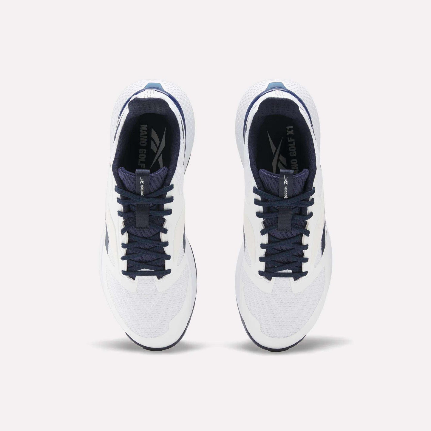 Top view of a pair of Reebok Nano Golf Shoes with white FlexWeave uppers, dark blue laces and accents. The performance shoes are side by side, facing forward on a light background.