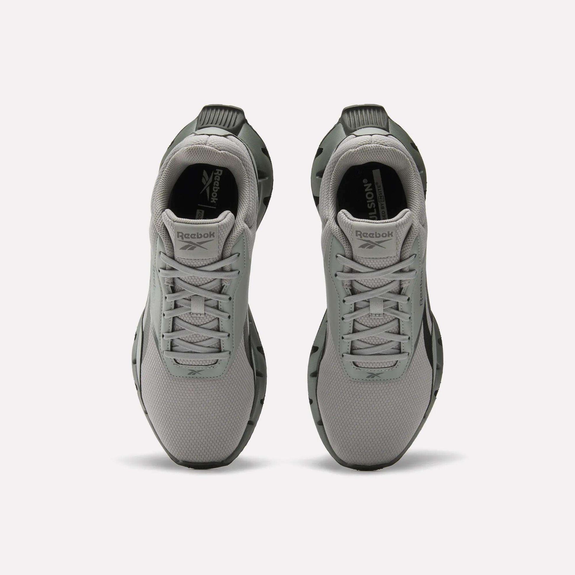 A pair of light gray Reebok Zig Dynamica STR Shoes viewed from above, featuring a mesh upper, lace-up fronts, black outsoles, plush EVA cushioning, and the Reebok logo on the tongue and insole.