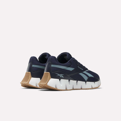 The Reebok Zig Dynamica STR Shoes feature a navy mesh upper, light blue side stripes, chunky white zigzag soles, and tan rubber outsoles, shown against a plain white background.