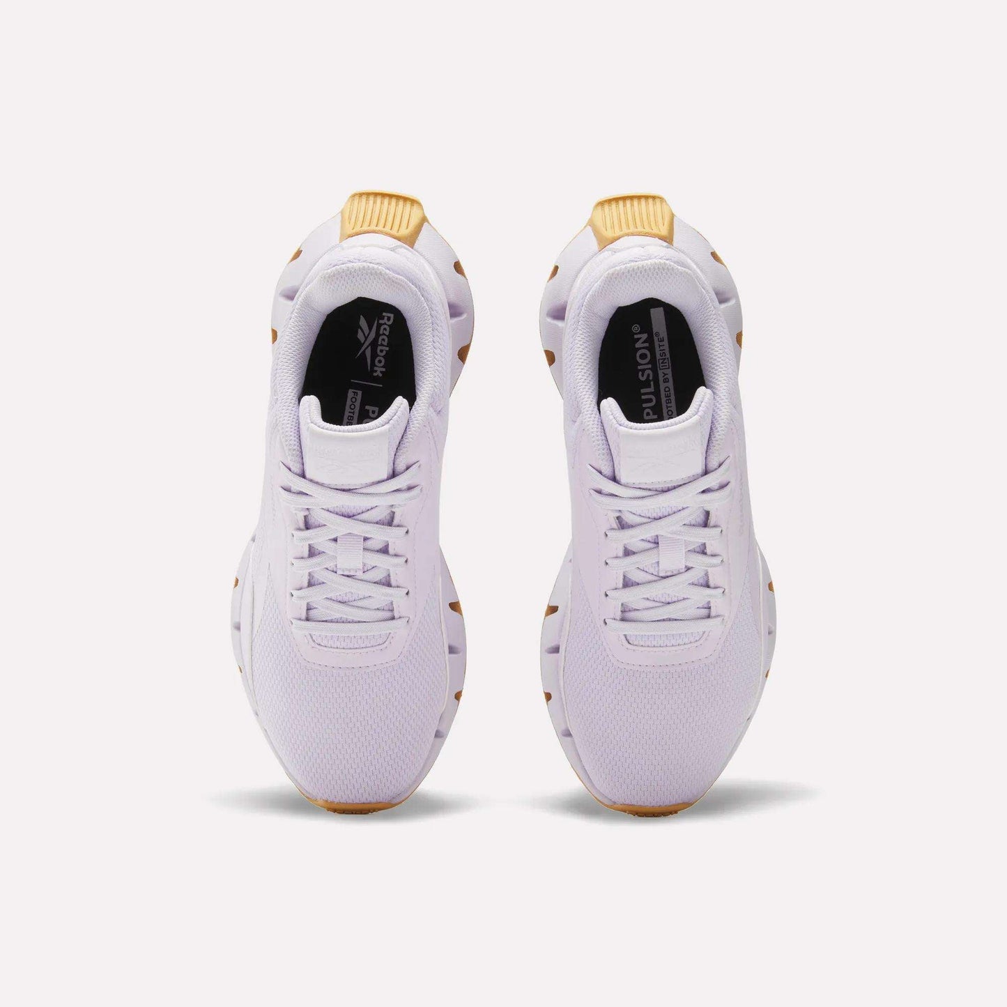 The Reebok Women's Zig Dynamica STR Shoes are white athletic sneakers with breathable mesh uppers and tan accents on the heels and soles, shown from above against a plain light background.