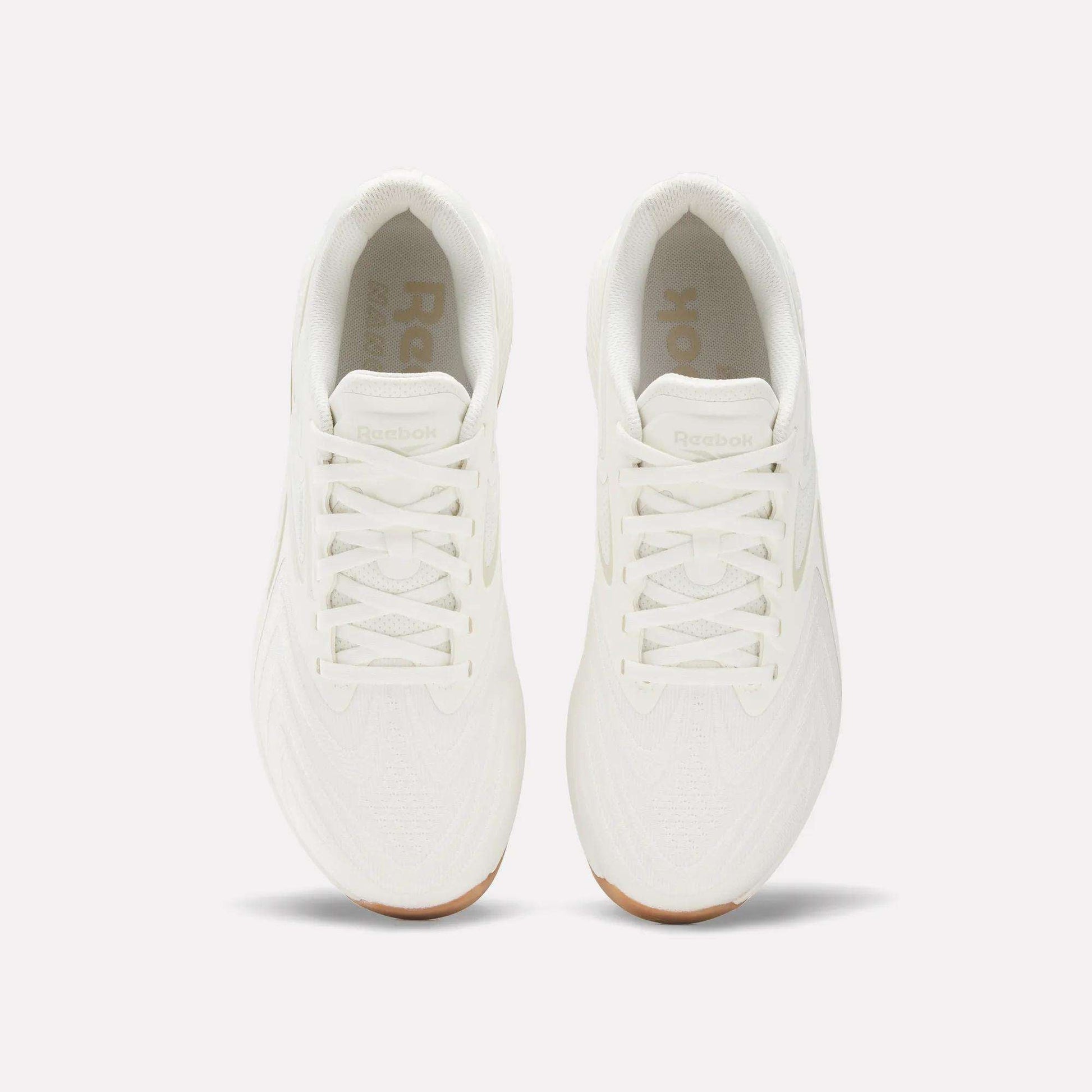 Top view of Reebok Nano X5 Edge Training Shoes in all-white with white laces and gum soles, placed side by side on a plain light background, designed for peak performance.