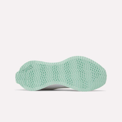 The Reebok Women's Zig Dynamica STR Shoes feature a light green outsole with a wavy, herringbone pattern, designed for innovation in running, displayed against a white background.