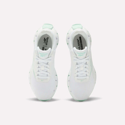 A pair of Reebok Women's Zig Dynamica STR Shoes in white with mint green accents, featuring breathable mesh for comfort, shown from above on a plain white background.