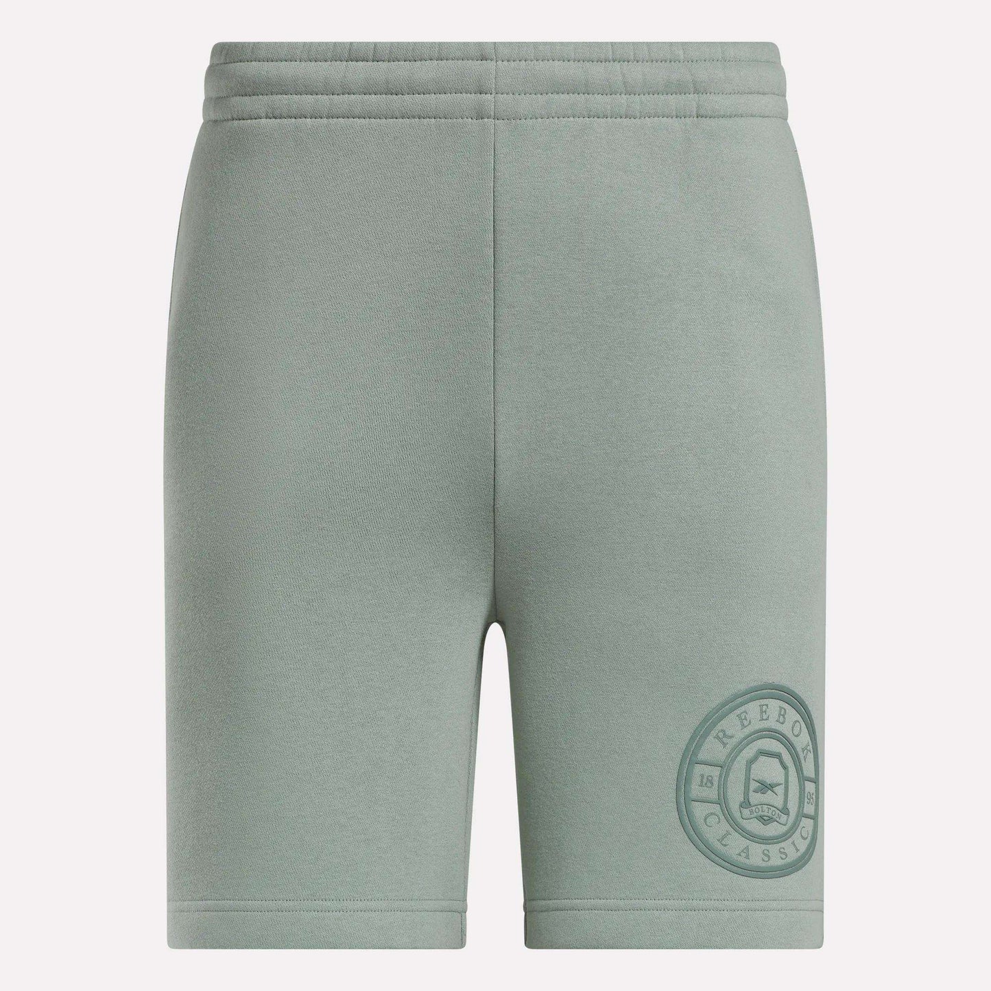 Light green Men's Crest Shorts by Reebok featuring a relaxed fit, elastic waistband, soft cotton fabric, and a darker green circular Reebok Classic logo near the left hem. Front view shown.