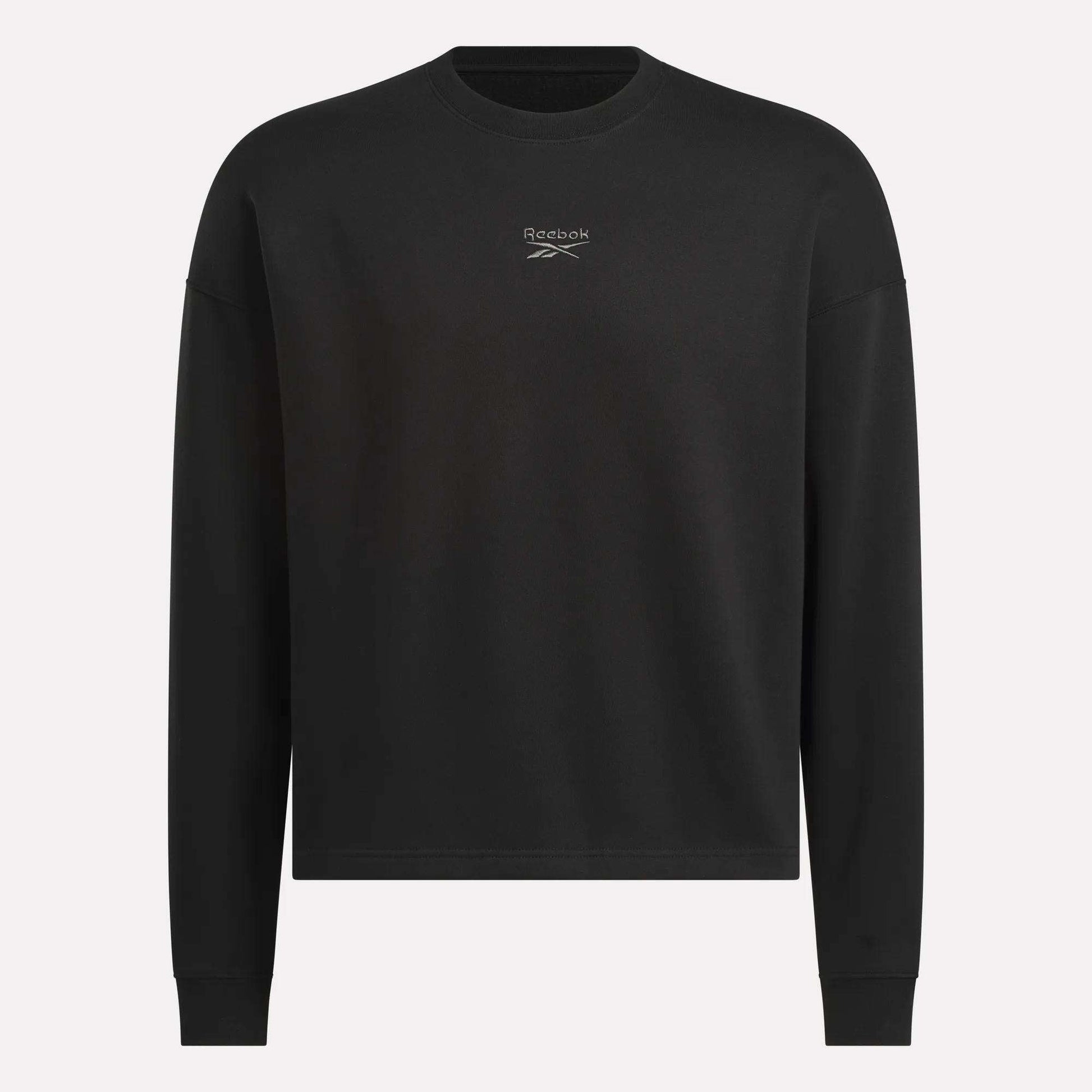 The Men's Wardrobe Essentials Sweatshirt by Reebok is a plain black, relaxed-fit design with long sleeves and a small white logo on the chest. Made from soft cotton-blend fleece. Shown against a light gray background.