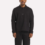 A man wears the Reebok Men's Wardrobe Essentials Long Sleeve Polo Shirt with a chest logo and relaxed fit, standing against a plain white background.
