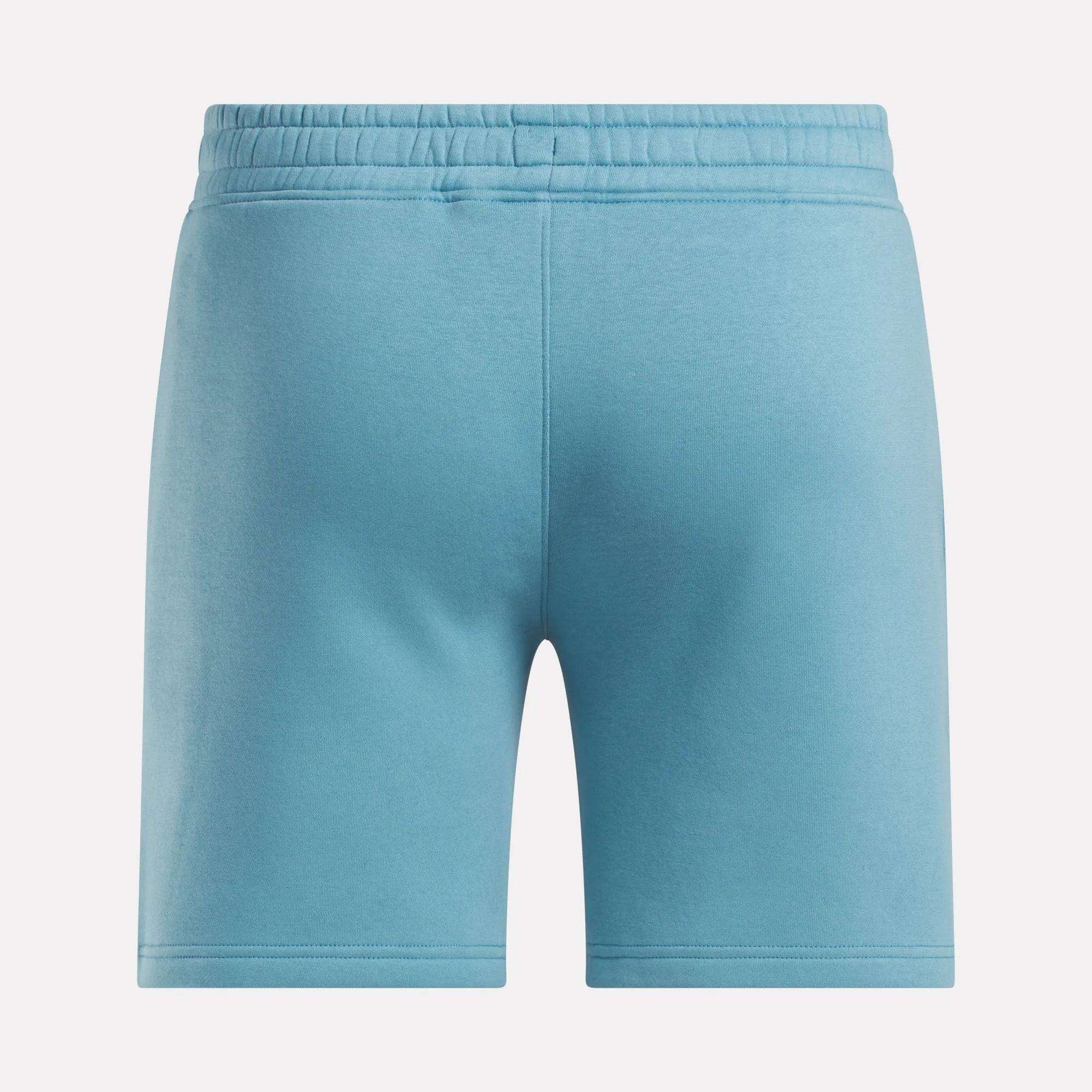 Men's Wardrobe Essentials Shorts by Reebok in light blue, shown from the back with an elastic waistband and relaxed fit. Made from soft fleece for comfort, these shorts have a clean design with no visible logos or patterns—ideal for daily wear.