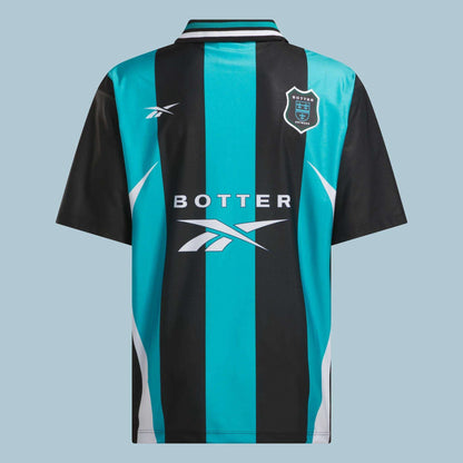The Reebok x Botter LTD Reverse Soccer Men's Tee features black and teal vertical stripes, a collared design, white side accents, and chest logos including “Botter 1978.” This vintage-inspired jersey merges classic style with Reebok branding.