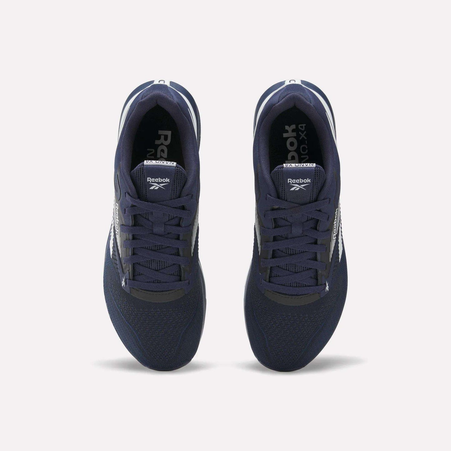 Top view of a pair of Reebok Nano X4 Training Shoes in navy blue, featuring white soles and side logos, crafted with Flexweave material, displayed on a plain light background.